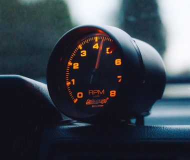 A glowing RPM gauge mounted on a car dashboard, emphasizing speed and automotive focus.